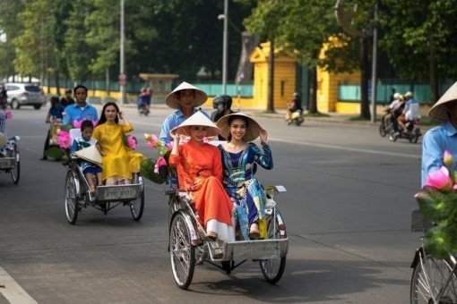 Vrouwen in traditionele ao dai nemen fietstaxi